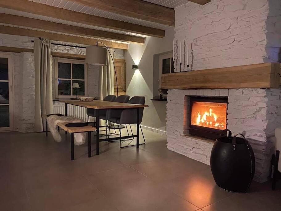 a living room with a fireplace and a table and chairs at Charmante maison de vacances in Vaux-sur-Sûre