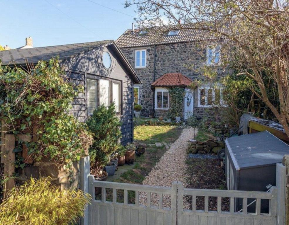 une maison en pierre avec une clôture devant elle dans l'établissement 4 bedroom coastal cottage with walled garden, à Embleton