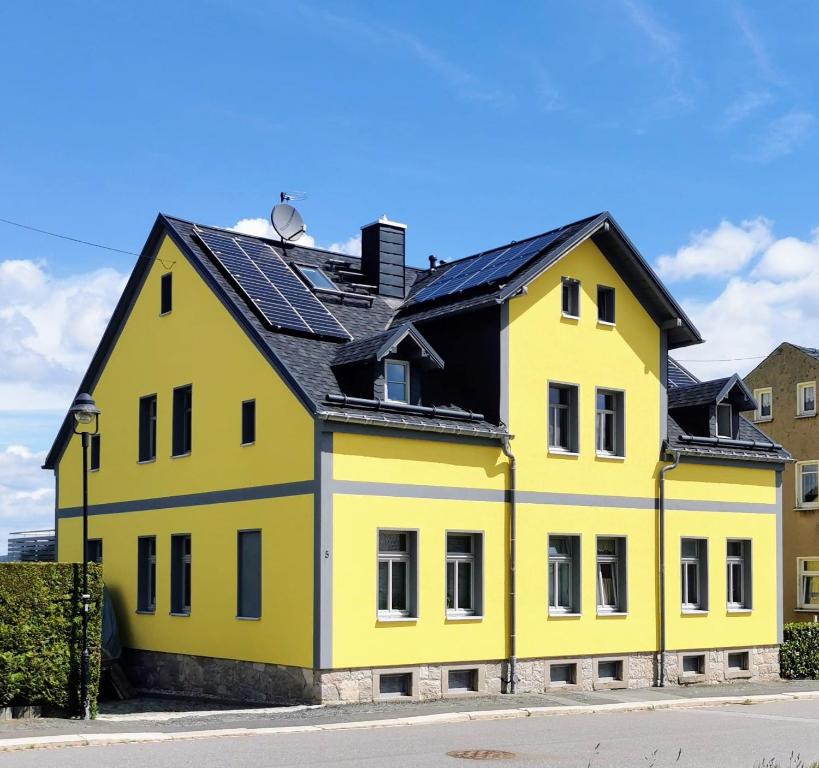 une maison jaune avec un toit noir dans l'établissement Fewo Klöppel Auersbergblick, à Eibenstock