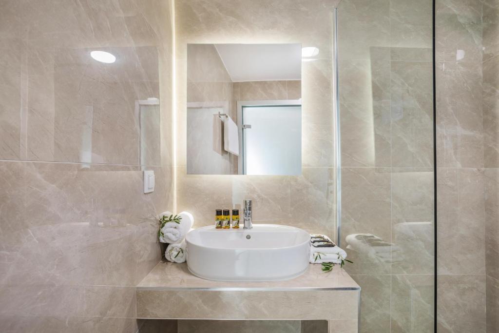 a bathroom with a white sink and a shower at AlexMare Hotel Fourka in Skala Fourkas