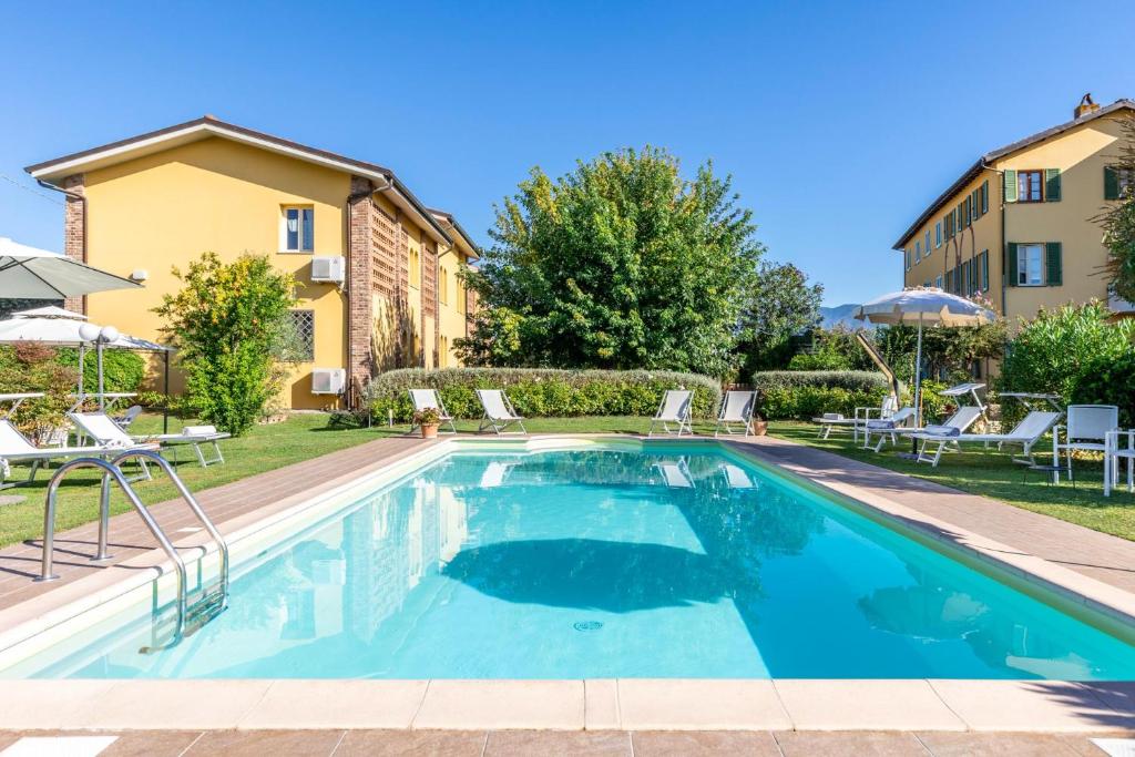 - une piscine dans une cour avec des chaises et un bâtiment dans l'établissement Villa Gabriella, à Lucques