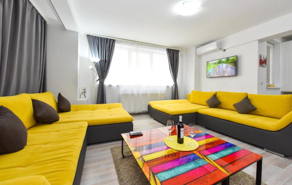una sala de estar con sofás amarillos y una mesa colorida. en Bucharest Accommodation Apartments, en Bucarest