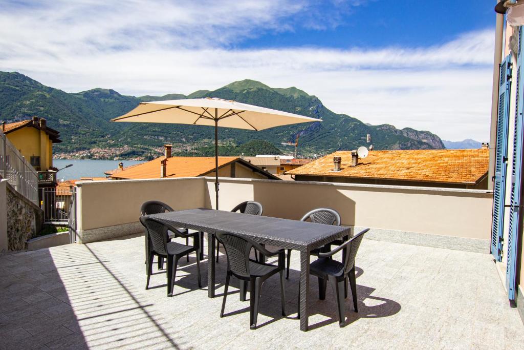 une terrasse avec une table, des chaises et un parasol dans l'établissement APPARTAMENTO PERSEO, à Lezzeno