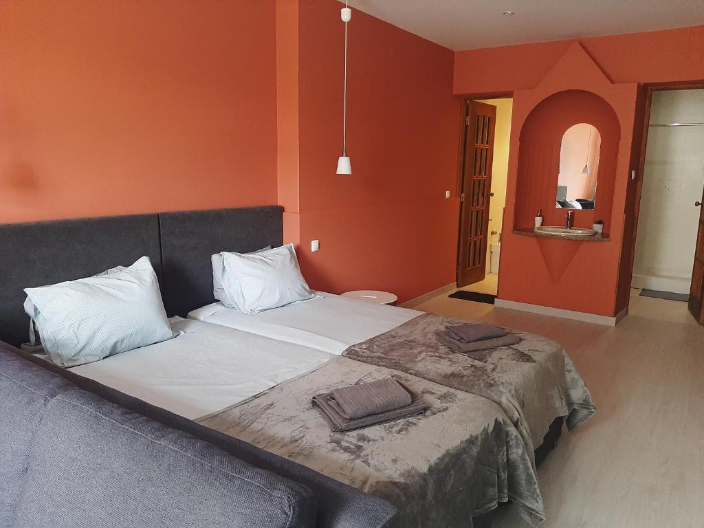a bedroom with a large bed with orange walls at Quartos Do Seixe - Laranja in Odeceixe