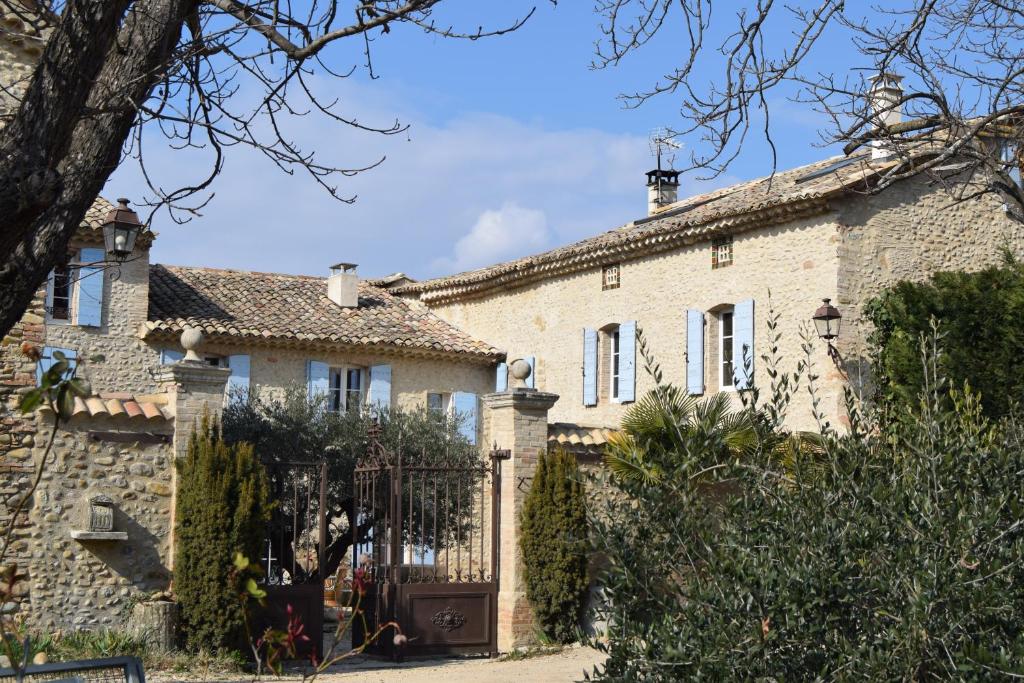a stone house with a gate in front of it at Gite Le Figuier - La Roseraie du Val'ensoleillé in Valensole