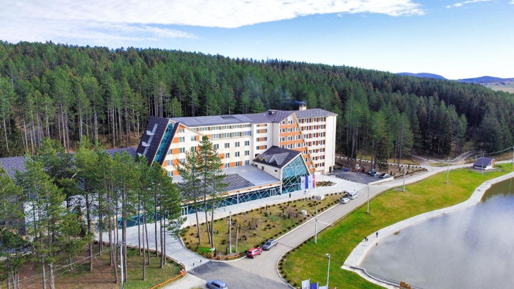 z góry widok na budynek z jeziorem i drzewami w obiekcie Hotel Borovi Forest Resort & Spa w mieście Sjenica
