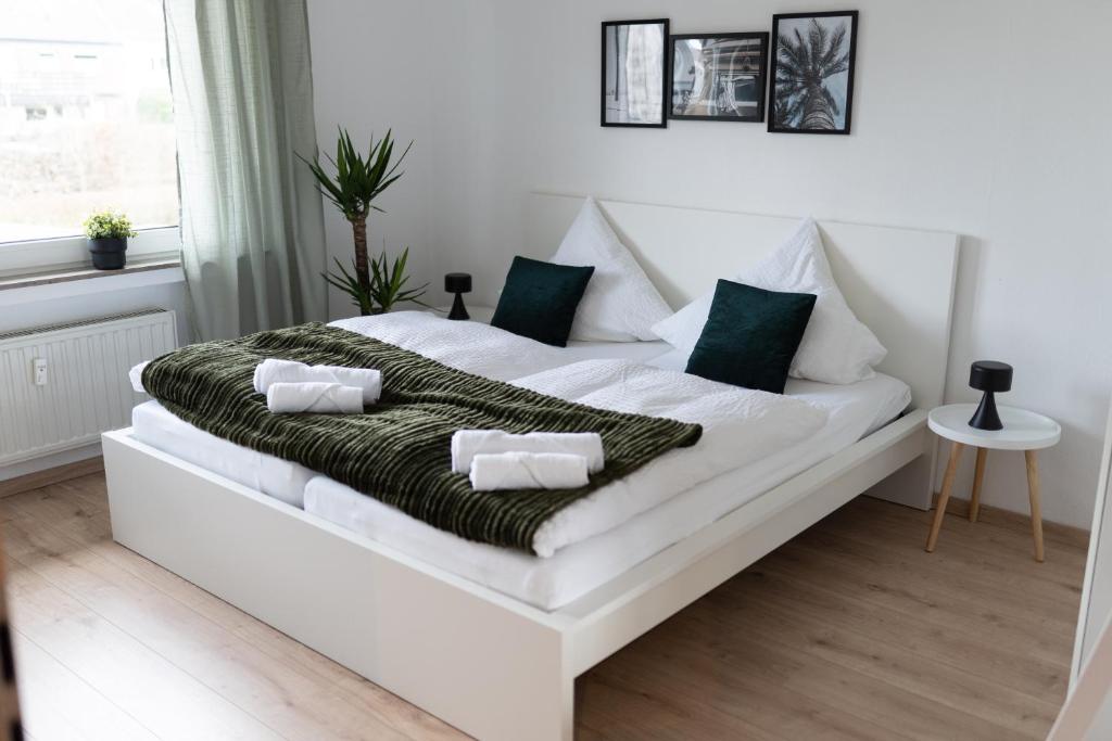 a white bed with green and white pillows on it at Modern 3Room Apartment Free Wifi Netflix and free Parking in Hamm