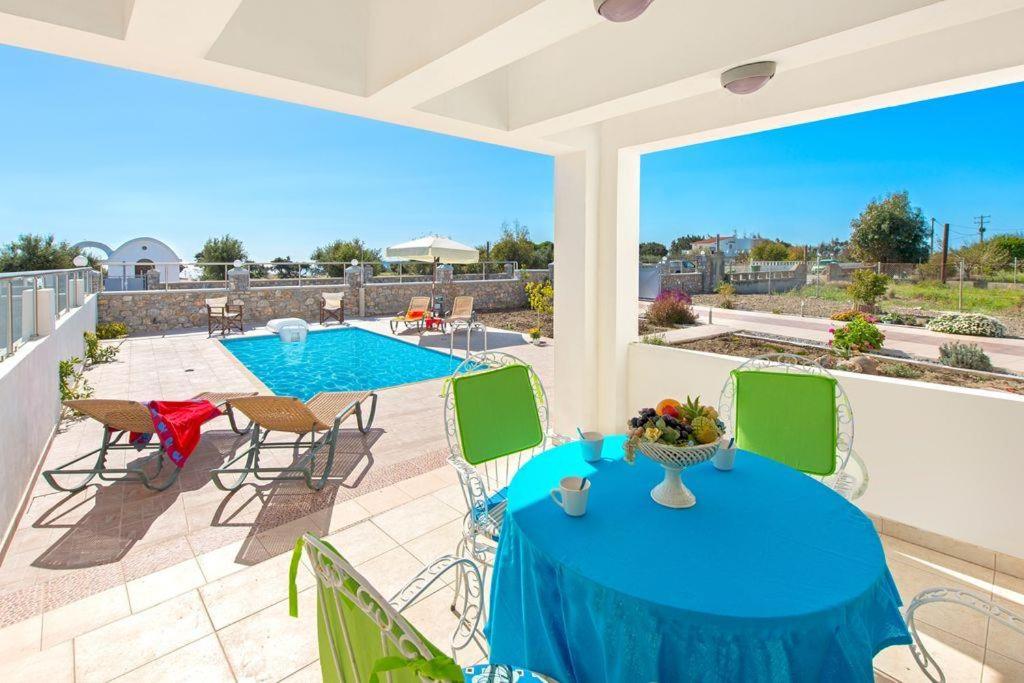 un patio avec une table et des chaises et une piscine dans l'établissement Pearl Villas Gennadi, à Gennadi