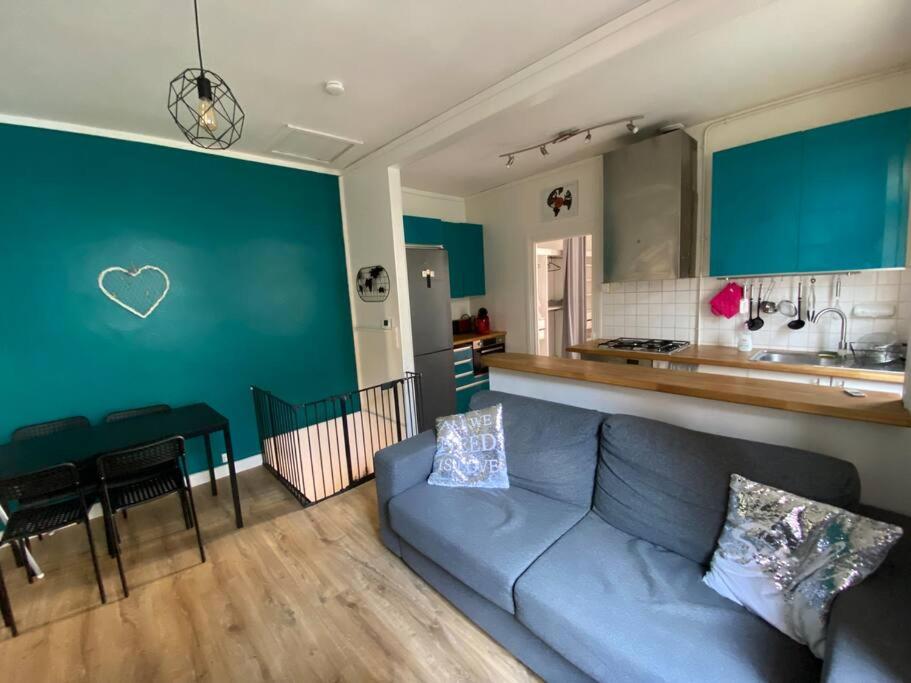 ein Wohnzimmer mit einem blauen Sofa und einer Küche in der Unterkunft Maison de ville Orléans dans le Quartier Dunois avec parking privatif in Orléans