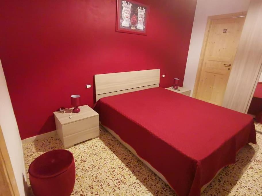a red bedroom with a bed and a red wall at NA ZA ROSA in Porto Empedocle
