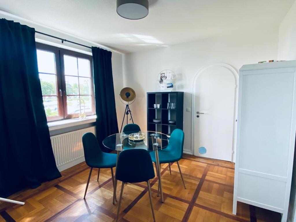 une salle à manger avec une table en verre et des chaises bleues dans l'établissement Dümmer Perle Apartments, à Hüde