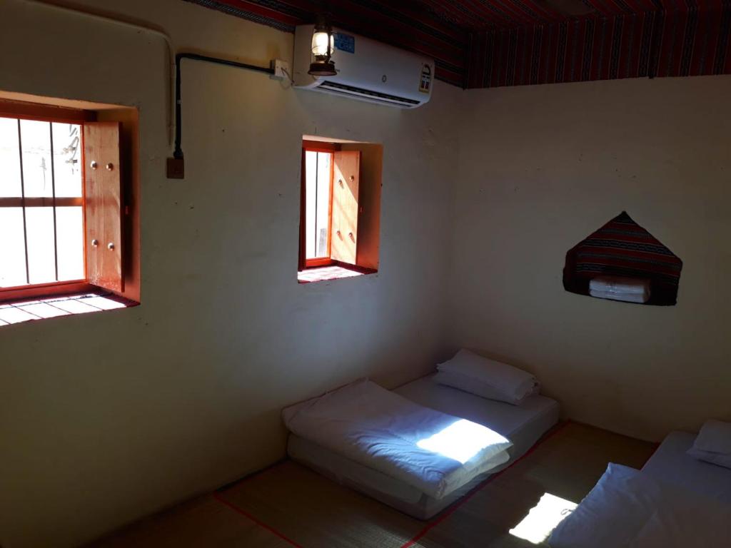 Balad Sayt Heritage Inn في Bilād Sayt: غرفة بسريرين ونوافذ