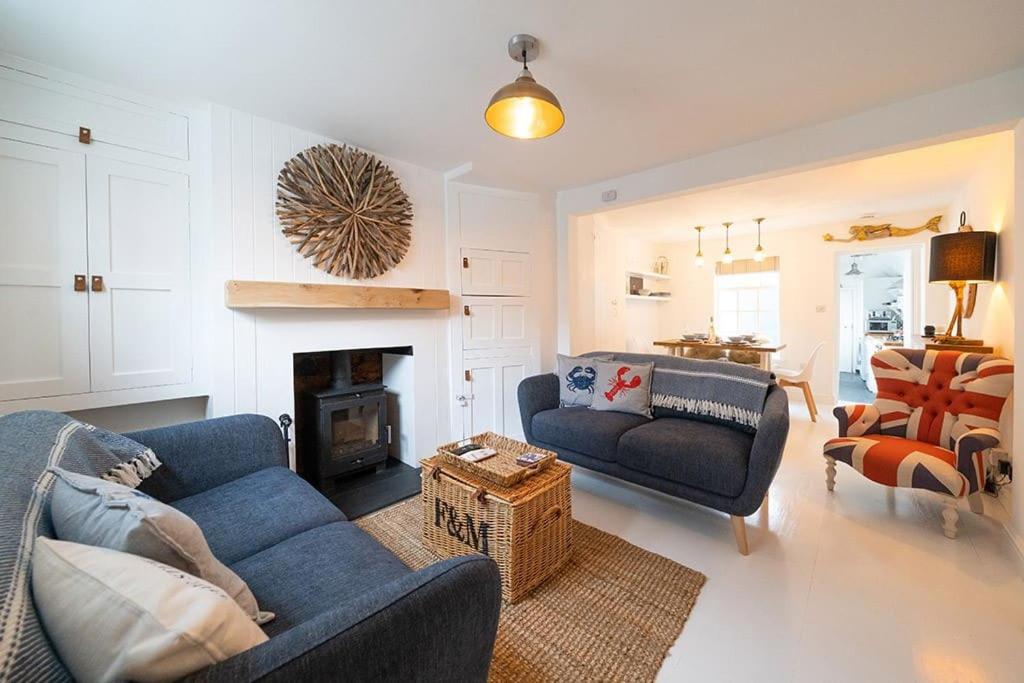 a living room with two blue couches and a fireplace at Fisherman's Cottage, Whitstable in Whitstable
