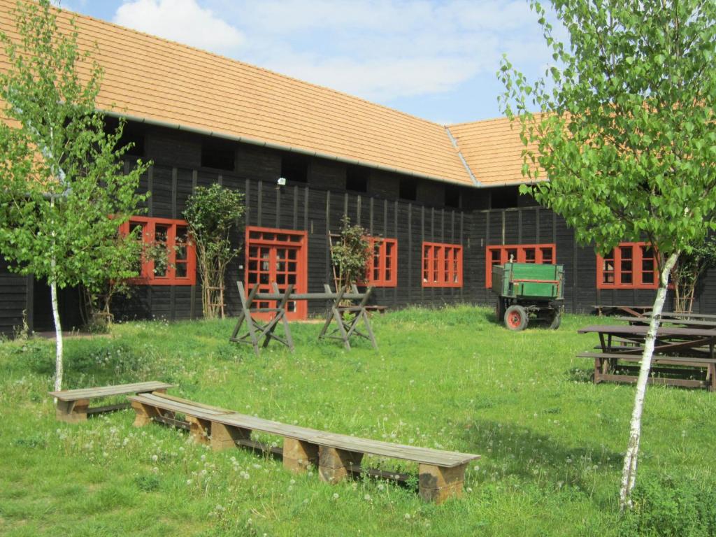 a building with red windows and a green truck in the yard at Sóstói Lovaskemping és Turistaház in Nyíregyháza