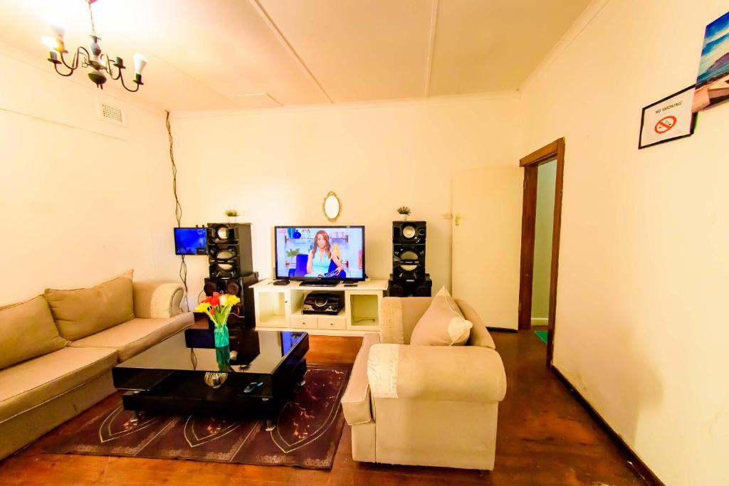 a living room with a couch and a tv at Daven Guest House (DGH) in Pietermaritzburg