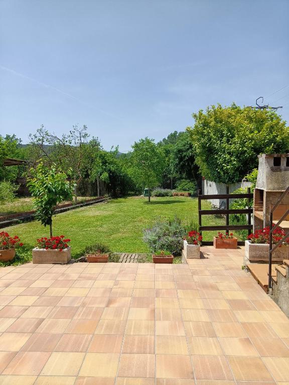 a patio with potted plants and a grass field at Casa rural ideal para familias y amigos in Serinyà