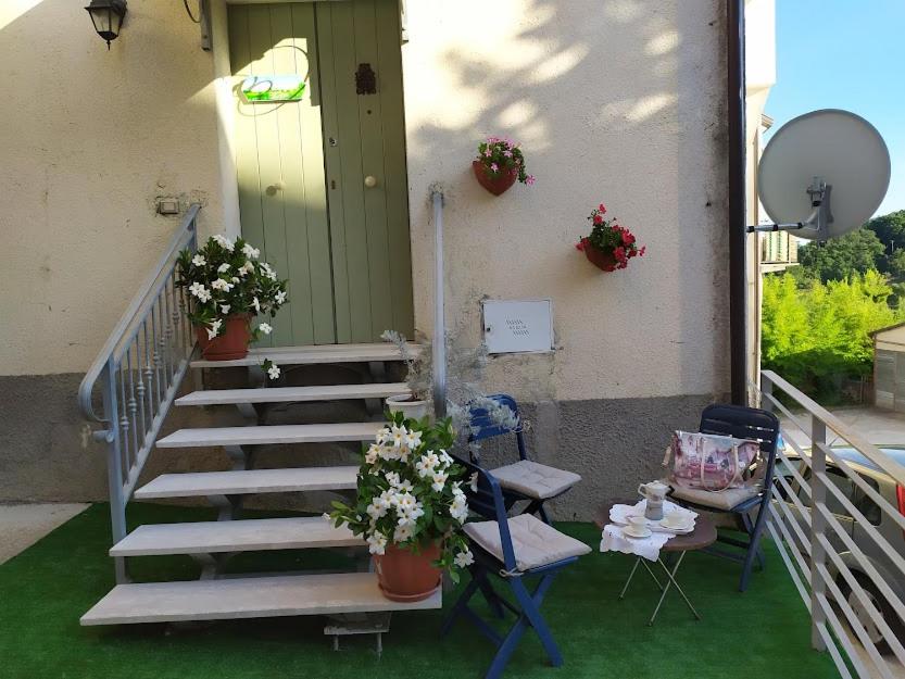 een veranda met een trap, 2 stoelen en een tafel met bloemen bij Jolie Petite Maison in Campolattaro
