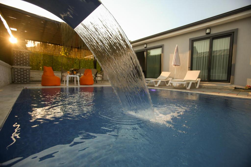 a pool with a water fountain in front of a house at Talia Villalari in Fethiye