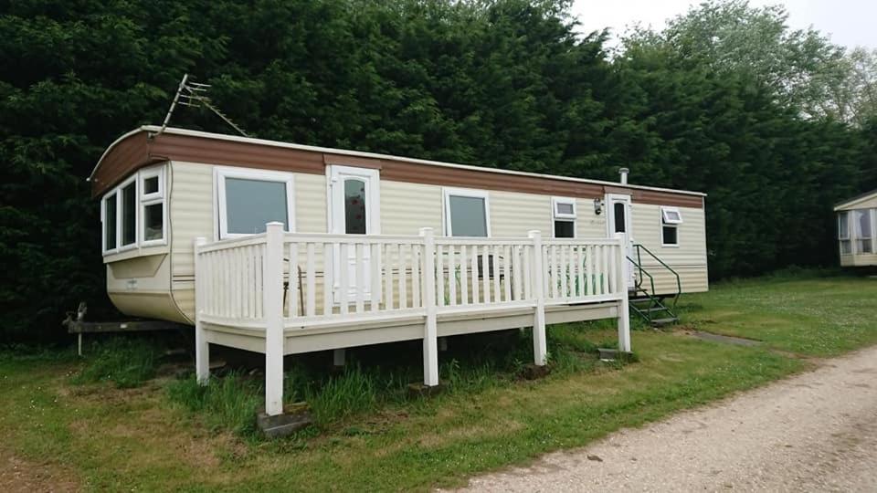 a mobile home with a porch and a boat at Kestral Pet Friendly Caravan in Alford