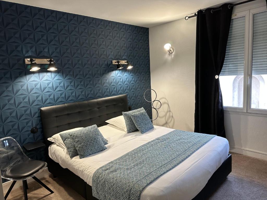 a bedroom with a large bed and a chair at Hotel Le Saint-Yves in Le Tréport