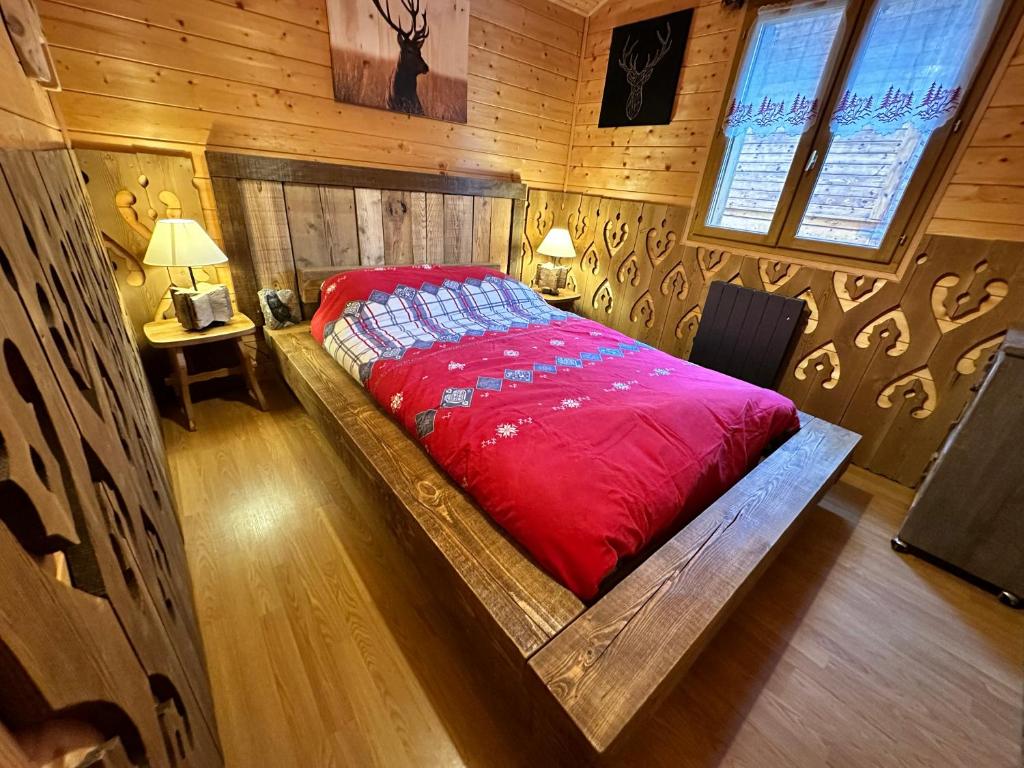 1 dormitorio con 1 cama roja en una habitación de madera en Refuge des Cimes, en Saint-Laurent-en-Grandvaux