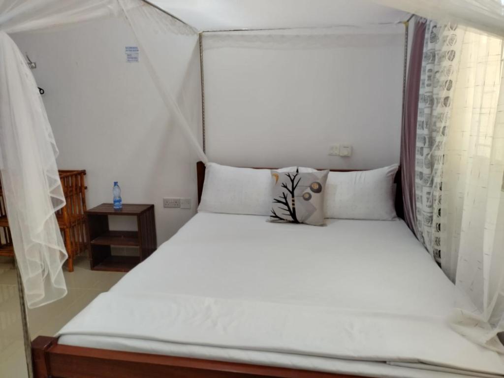 een bed met witte lakens en kussens in een kamer bij 6 Park Retreat in Mombasa