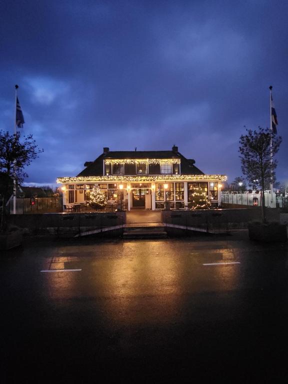 un bâtiment allumé la nuit avec des lumières allumées dans l'établissement Café Brasserie Het Heerenhuis, à Het Kalf