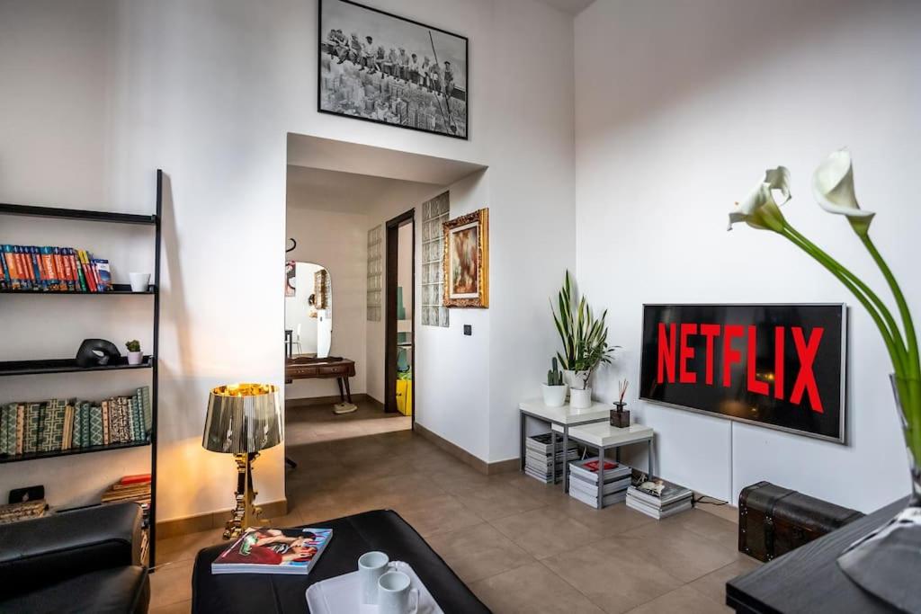 a living room with a television on a wall at Life is Beautiful Design LOFT Navigli Romolo, SmartTV, WiFi, AC and street parking in Milan
