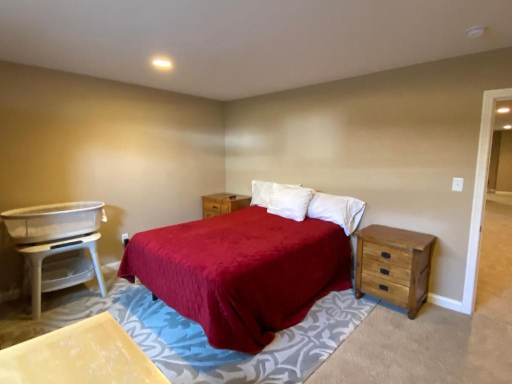 1 dormitorio con cama roja y piano en Private basement bedroom with private bathroom, kitchen, and living room with large screen television, en McCordsville