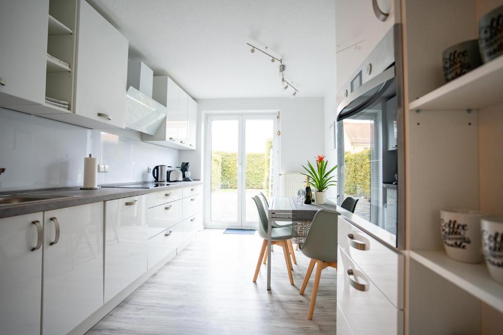 a kitchen with white cabinets and a table with chairs at CaSa Apartment Svea - 2x Parken-Amazon Prime-Terasse-Garten-Vollausstattung in Erfurt