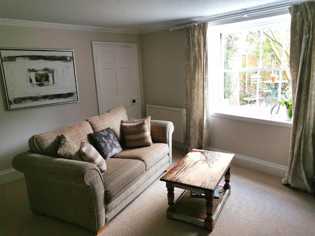 a living room with a couch and a coffee table at Beehive Cottage in Beccles