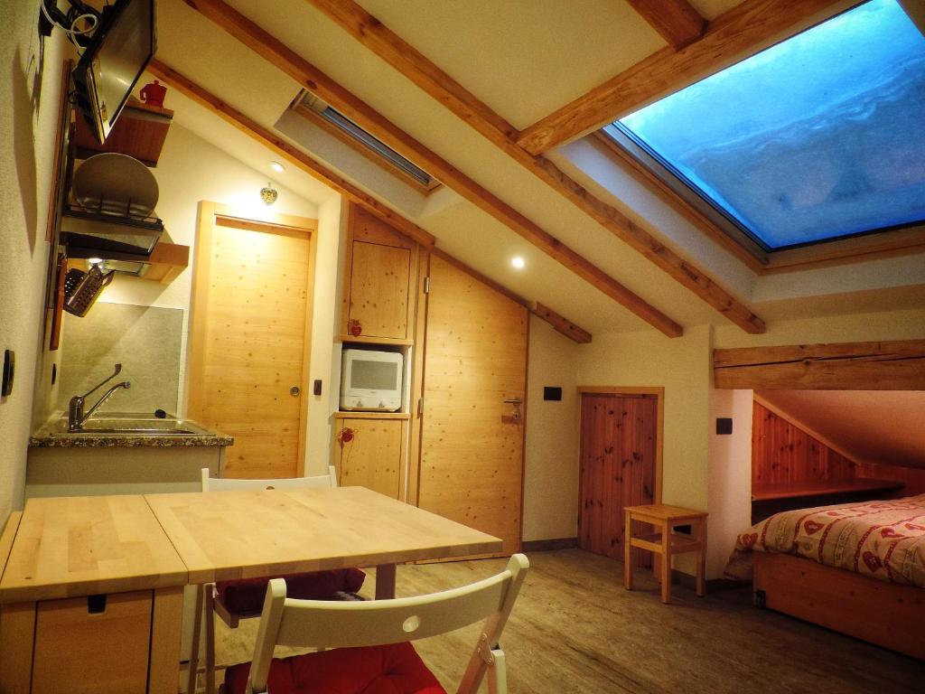 a room with a table and a bed and a window at incantevole mansarda in val di Fassa in Alba di Canazei
