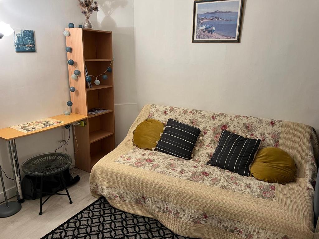 een woonkamer met een bank met 2 kussens bij Studio cosy et confortable collé à La Défense in Courbevoie