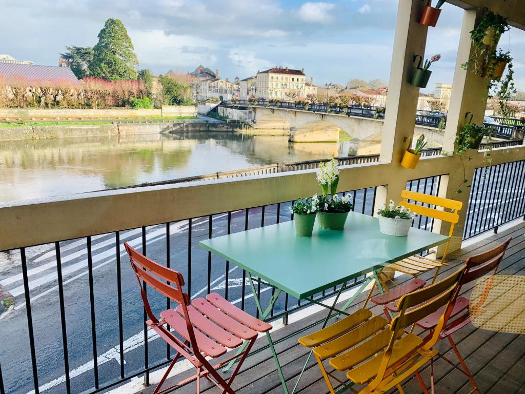 un tavolo e sedie su un balcone affacciato su un fiume di "Au Fil de la Charente" - Coeur de Saintes - WIFI Clim - Classé 4 étoiles - 4 pers a Saintes