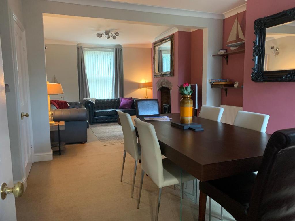 a dining room with a wooden table and white chairs at Smart & Comfortable 3-bedroom Victorian house in Stalham