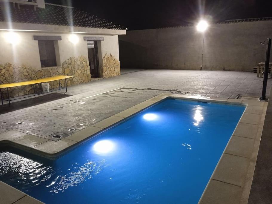 una gran piscina azul en un edificio por la noche en El capricho de Diego en La Puebla de Montalbán