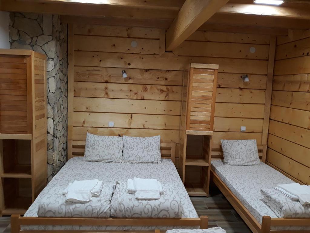 two beds in a room with wooden walls at Vila Kula in Crni Vrh