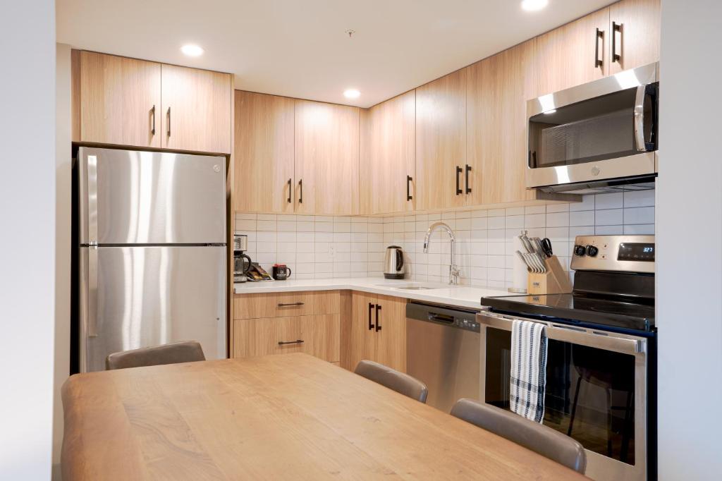 a kitchen with wooden cabinets and a wooden table at Basecamp Suites Banff in Banff