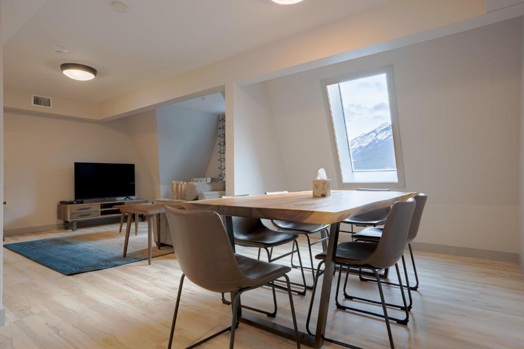 a dining room with a table and chairs and a television at Basecamp Suites Banff in Banff