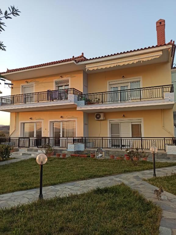 a large yellow house with balconies and a yard at Irini's appartment in Néa Koútali