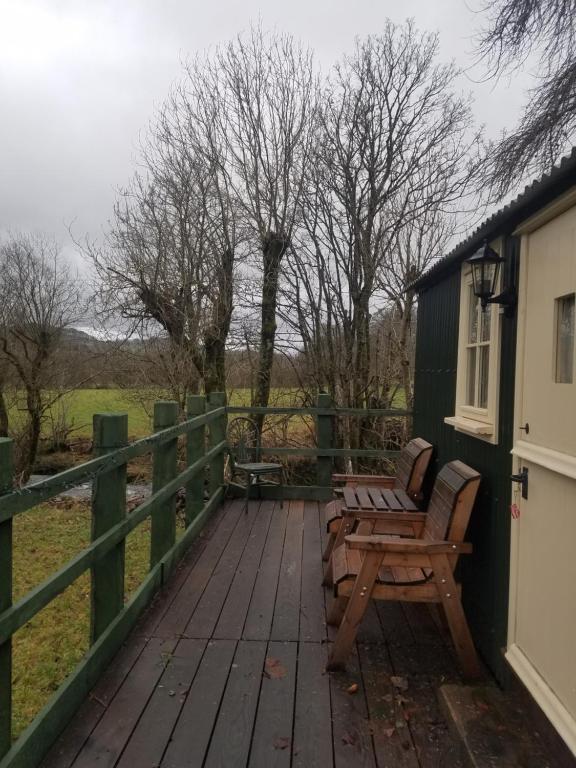 a wooden deck with two chairs and a fence at Rhydydefaid Cwt Clyd - Cosy Hut in Bala