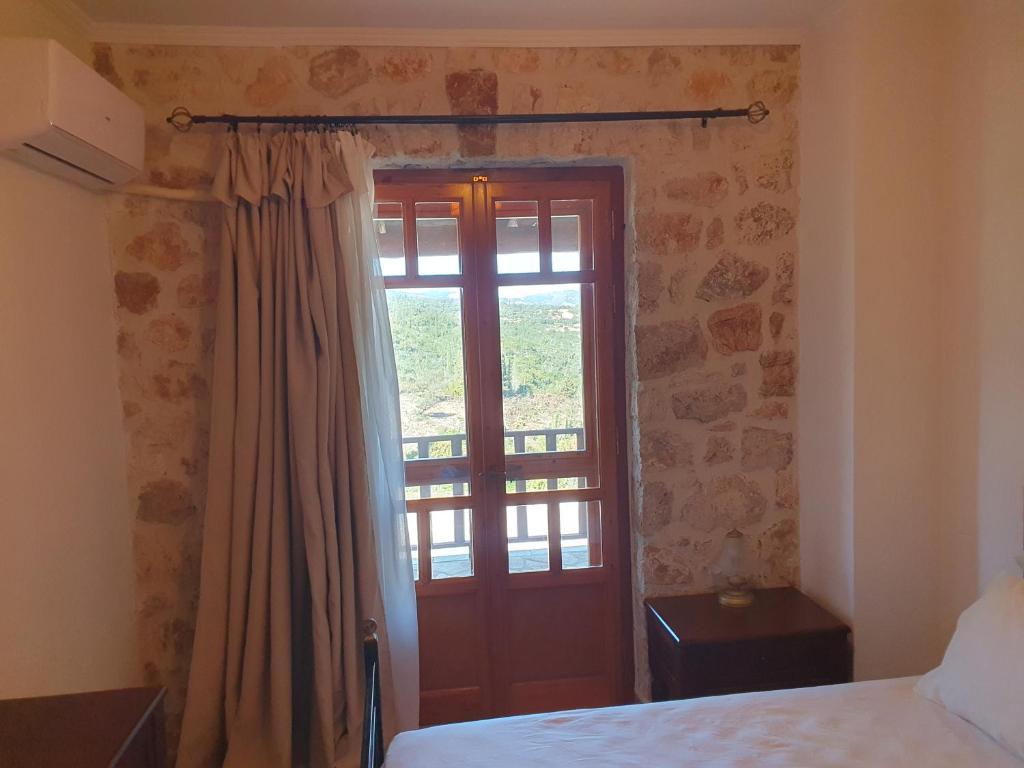 a bedroom with a bed and a door with a window at Nireas : Stone Villa in Zakynthos