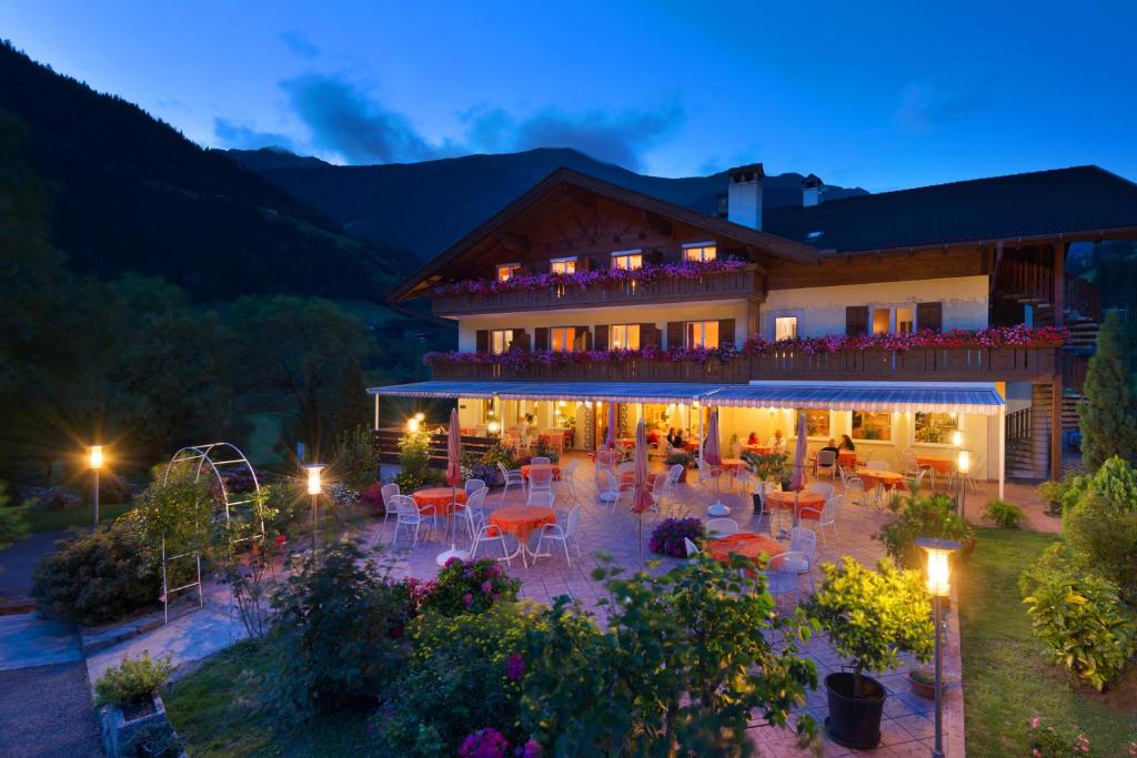 - un bâtiment avec une terrasse dotée de tables et de chaises la nuit dans l'établissement Hotel Klotz, à San Leonardo in Passiria