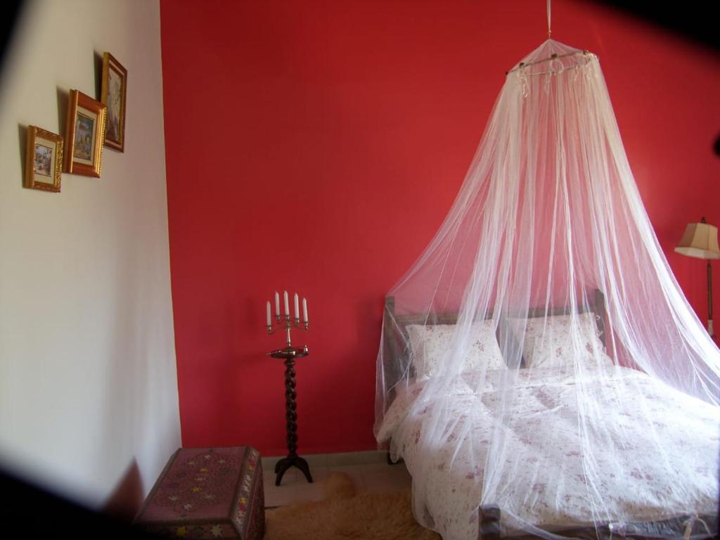 - une chambre rouge avec un lit et une moustiquaire dans l'établissement ferme Walila, à Douar Doukkara