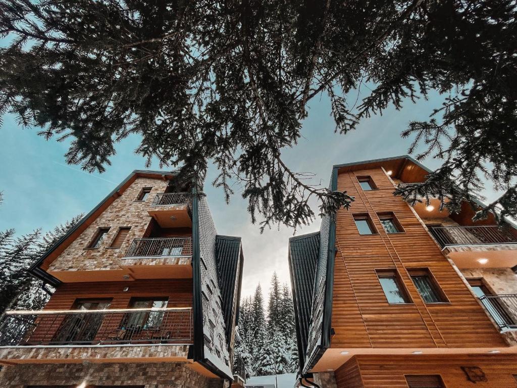 a view of two tall buildings with trees in the foreground at Vila Jelena in Jahorina