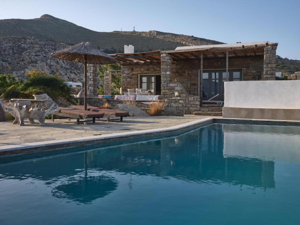 a swimming pool with a table and an umbrella at VILLA ALEXANDROS in Naousa