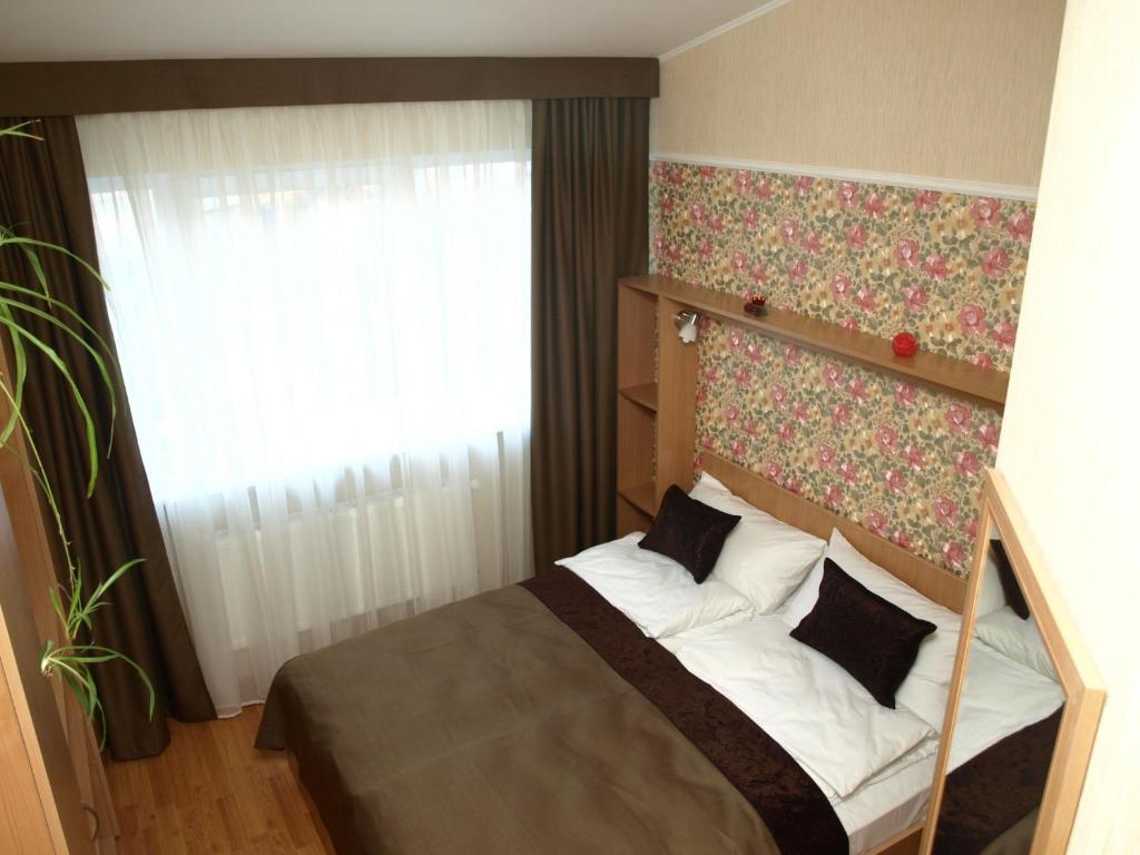 a bedroom with a bed with a floral headboard and a window at Leon Hotel in Lviv