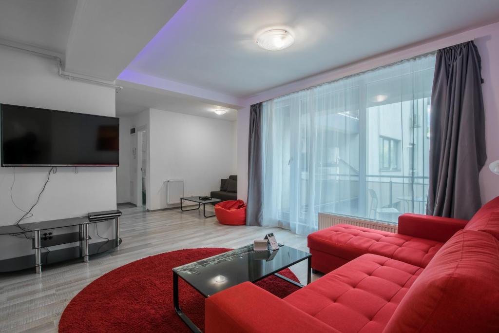 sala de estar con sofá rojo y TV de pantalla plana en Royal Accommodation, en Bucarest