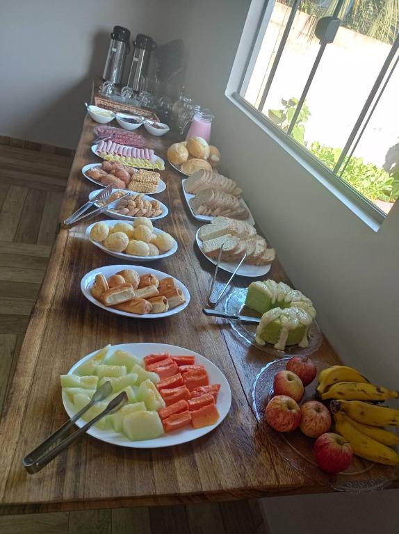 a long wooden table with plates of food on it at Pousada Aconchego in Ametista do Sul