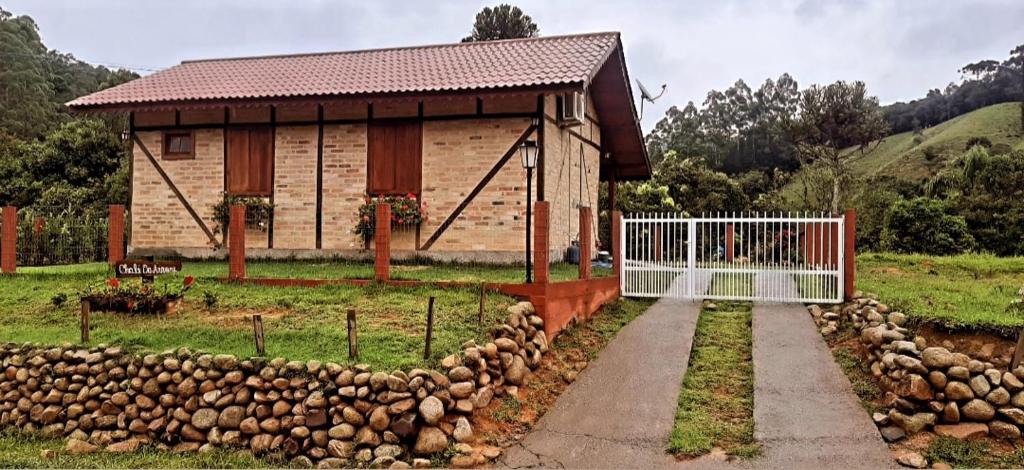 a building with a gate in front of a yard at Caminhos da Serra do Tabuleiro - Chalé das Árvores in São Bonifácio